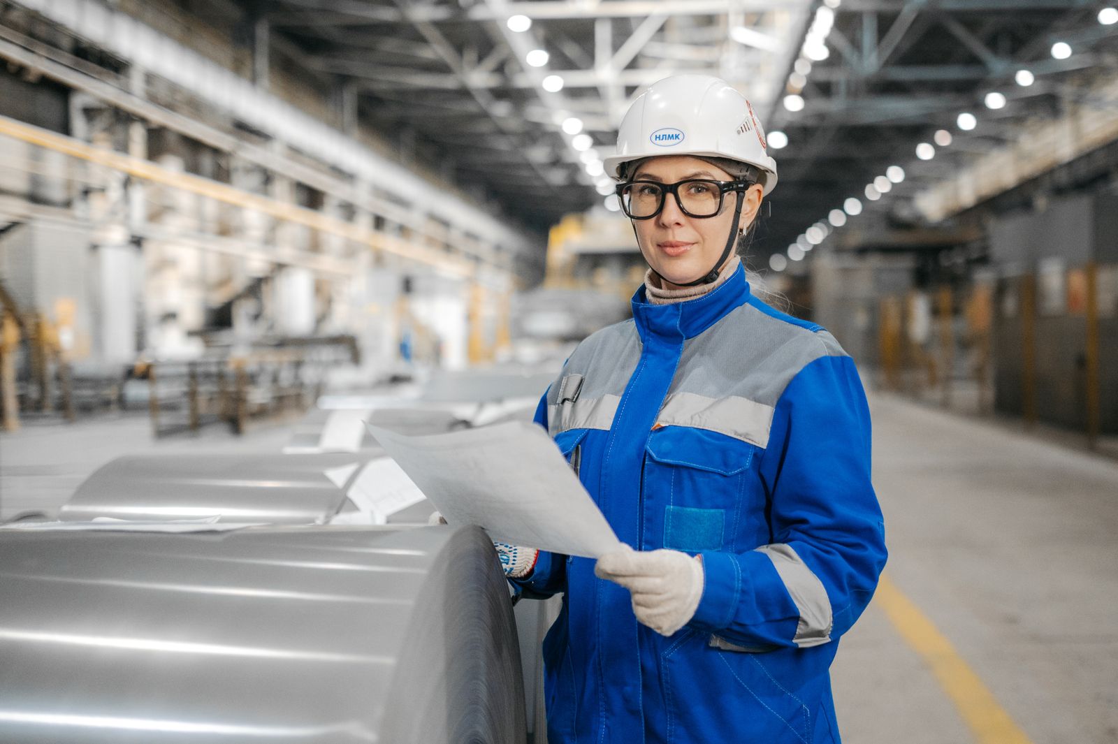 Engenheira com capacete inspecionando produção em fábrica